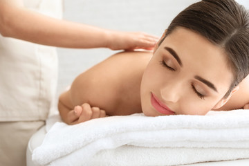 Young woman having body scrubbing procedure with sea salt in spa salon