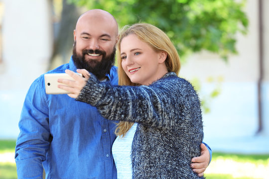 Overweight couple taking selfie in park
