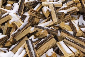 background - a messy heap of chopped logs lightly covered with fallen and melting snow