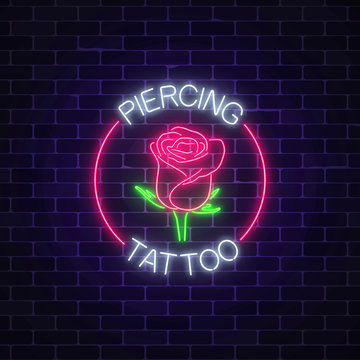 Tattoo and piercing parlor glowing neon signboard with rose emblem. Flower symbol in circle frame with text.