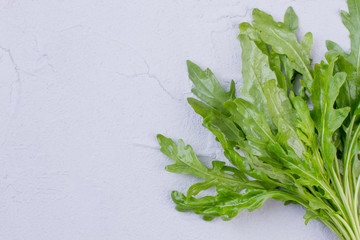 Bunch of fresh arugula, copy space. Close up green rocket on textured background and copy space.
