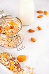Jar with homemade granola or oatmeal muesli with nuts and dried fruits and almond milk. Healty diet breakfast, vegan or vegeterian food concept