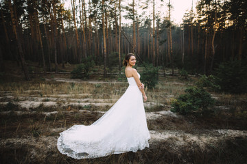 Beautiful bride. Wedding day. Very beautiful bride in a luxurious wedding dress and with red lipstick on her lips, standing on the nature in the forest and smiling