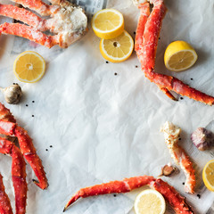 Top view of fresh crab phalanges with lemon and spices on rumpled paper with copy space. © PINKASEVICH