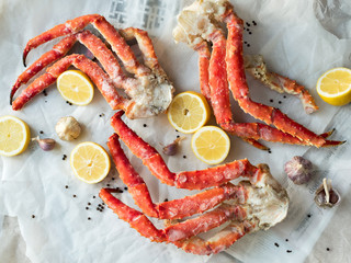Top view of fresh crab phalanges with lemon and spices on background of paper and newspapers 