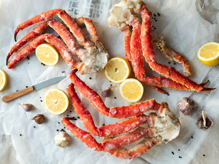 Top view of fresh crab phalanges with lemon and spices on rumpled paper. - Powered by Adobe