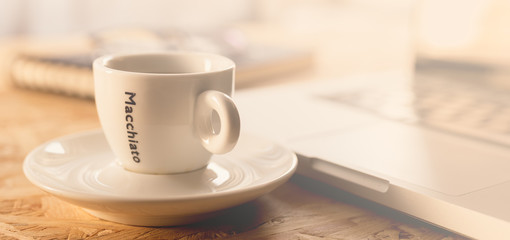 Coffee cup and laptop on coffee desk.