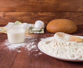 Flour, eggs, milk on a wooden background. Preparation of the dough.