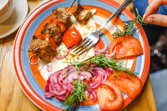 Turkish Traditional Meat Shish Kebab serving with onion, tomato and lavash on a plate in restaurant