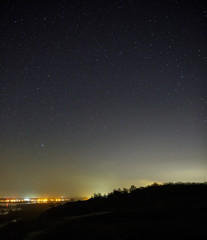 Starry sky at night over the city and forest. Landscape with a long exposure.