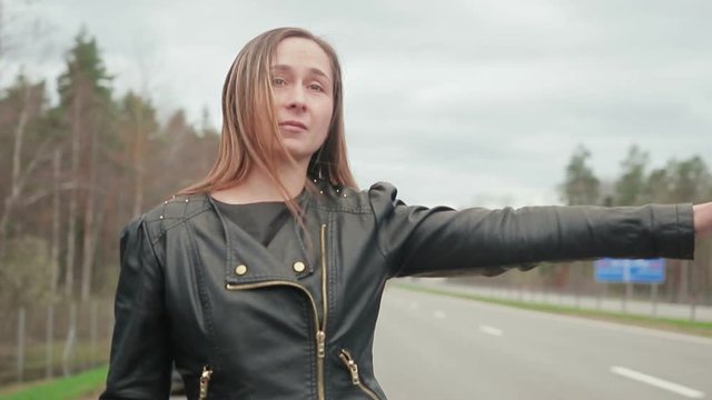 Young brown-haired woman stops for a ride near the broken machine. Handheld shot