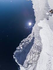 Aerial view of the border broken into pieces of different shapes and textures of ice and water 
