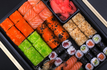 Big sushi set ib black plastic box on black background/ top view close up macro shoot