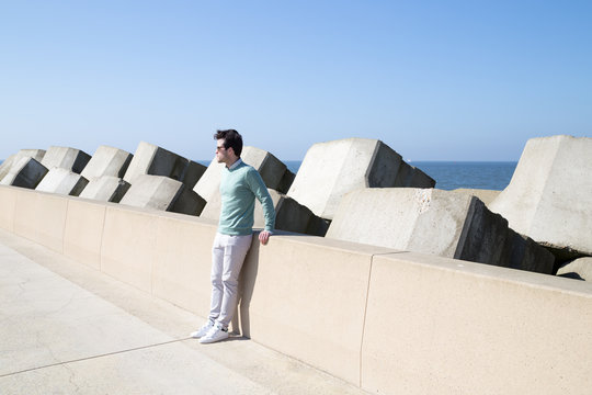 Young man leaning against seawall by the ocean