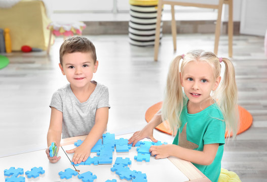Cute little children playing with puzzle at home