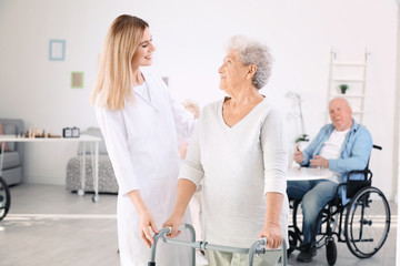Senior woman with walkers and nurse at care home