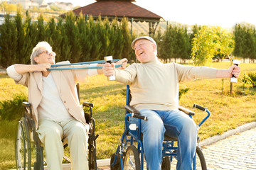 Senior man and woman from care home doing exercise outdoors