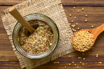 Whole grain mustard in glass jar, photographed overhead on wood natural light (Selective Focus,...