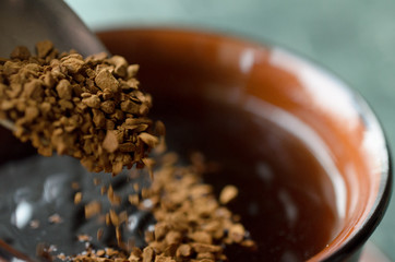 Spoon the granulated coffee into a cup for coffee.