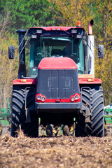 Fototapeta premium Rolnik w ciągniku przygotowuje ziemię z kultywatorem przedsiewnym