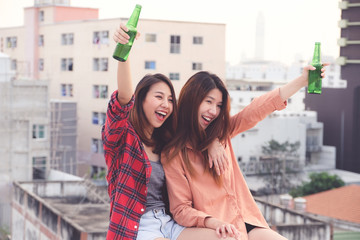 Two asian women drinking at rooftop party, outdoors celebration, LGBT couple