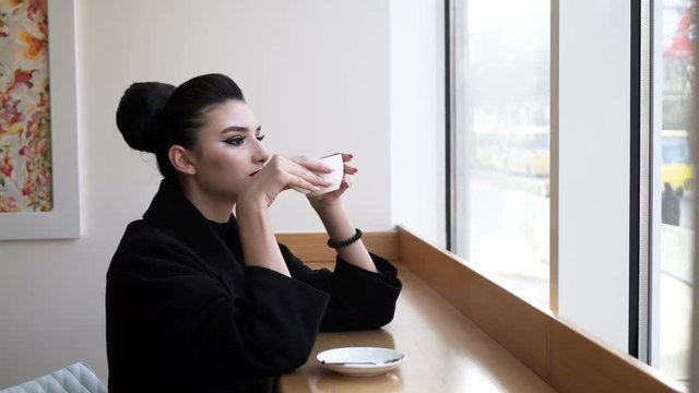 a young, beautiful woman drinking coffee