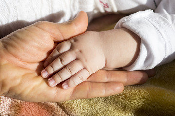 Holds the hand of the adult baby