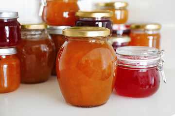Jars with different sweet jam on table