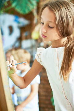 Portrait of talented pretty girl painting picture on easel in art class of development school