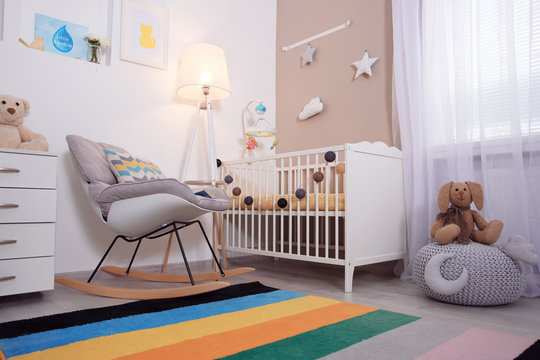 Cozy baby room interior with crib and rocking chair