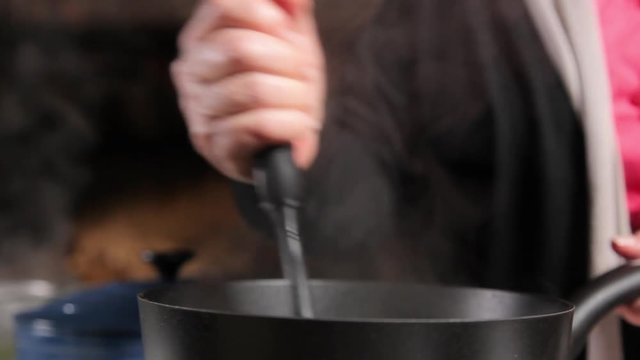 A close up shot of a woman smashing green pease in a pot.