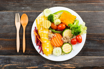 Vegetables salad with wooden spoon and fork on wooden background, top view
