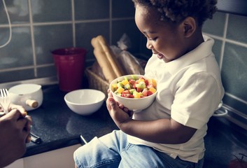 Black kid with fruit salad in the kitchen © Rawpixel.com
