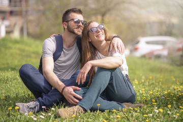 Fototapeta premium Happy young casual couple enjoying their time together in a grassy field covered with dandelions, celebrating spring time