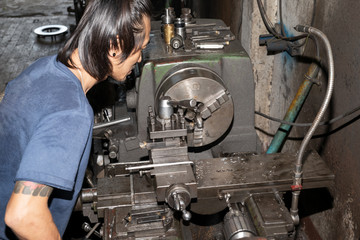 Man working on a lathe not wear protective personal equipment. Not safe for work