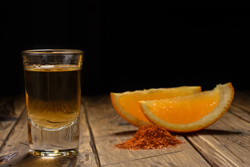 Mezcal shot - traditional Mexican drink with orange slices and worm salt on a old wooden table.