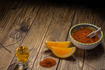 Mezcal shot - traditional Mexican drink with orange slices and worm salt on a old wooden table.