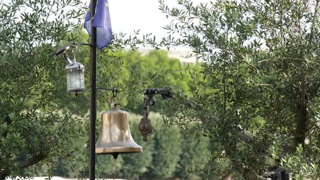 Close up of a gilded bell, a small lamp and a flag