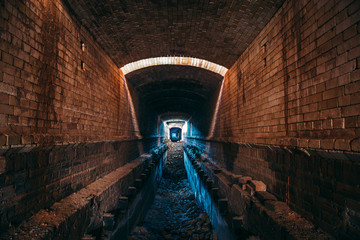 Long underground brick tunnel or industrial corridor, creepy and horror atmosphere, perspective