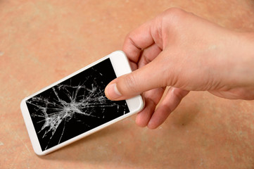 Person picking broken smart phone with cracked screen on the floor at home