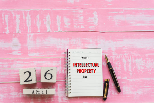 World Intellectual Property Day April 26, Wooden Block calendar note book and black pen on pink Pastel wooden table background texture.