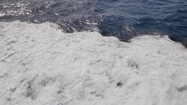 Background of water trail foaming behind a ferry boat.