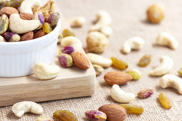 Dried fruits and variety of nuts into a bowl on wooden background. selective focus.