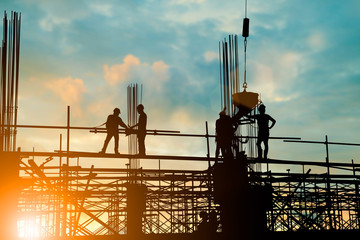 Silhouette of engineer and construction team working at site over blurred background sunset pastel...