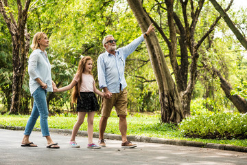 Happy family having fun together in the garden. Father, mother and daughter holding hands and walking in a park. Lifestyle concept