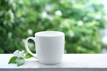 Cup of coffee on balcony in morning time with white flowers