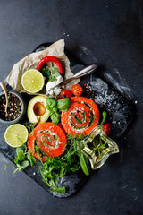 Delicious Salmon rolls, goats cheese in paper with knife, aromatic herbs, spices  on old black stone background, clean eating, healthy food, diet or cooking concept, top view, overhead, flat lay