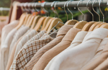 Obraz premium Clothes hang on wooden coat hangers in clothing store with nature tone.Soft focus.
