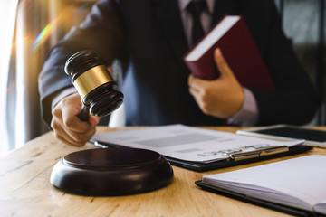 Justice and law concept.Male judge in a courtroom with the gavel,working with,digital tablet computer docking keyboard,eyeglasses,on wood table 
