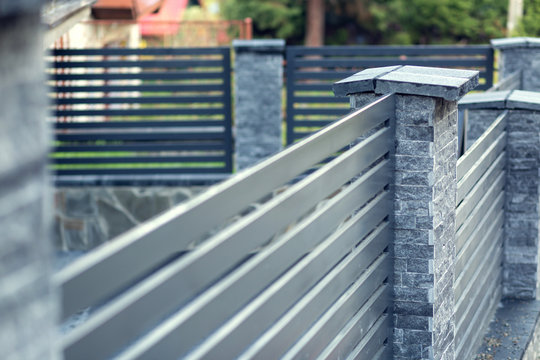 Modern fence with stone pillars and metal filling. Shallow depth of field with copy space.